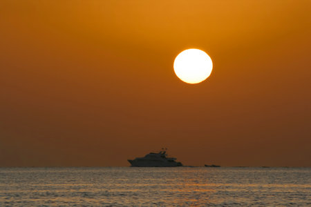 Morning seascape with silhouette of a pleasure ship and disk of the sun in the red sky. Sunriseの写真素材