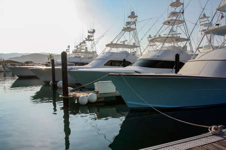 View of the parking lot of fishing and pleasure yachts in the morning sunlight and with glare....