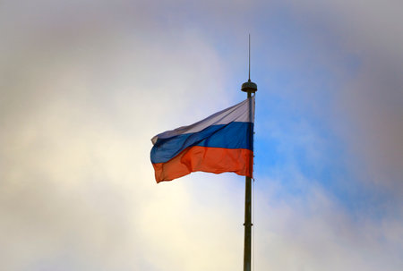 Flag of Russia in stormy sky with dark clouds on high flagpole. White-blue-red state flag of the Russian Federation is waving in the wind.の写真素材