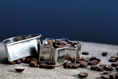 side view of cookie cutters filled up with coffee beans on a dark festive backgroundの写真素材