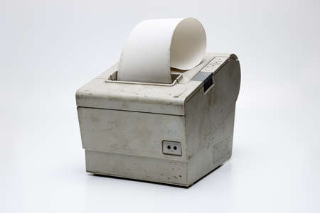 Profile view of an electronic receipt printer with a dirty and scratched surface on a white uniform...