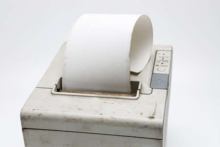 Old used receipt printer looking onto the top side of this device, with a mounted paper roll, copy...