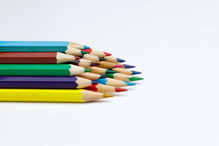 Side view of color pencils stacked with space on white uniform background, use for  presentations or websites, pencils are pointing to the rightの写真素材