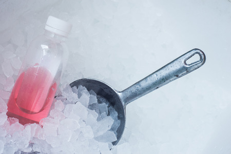 Metal spoon on ice cube background with rose drinkの写真素材