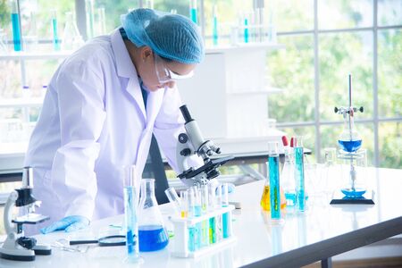 Asian woman scientist, researcher, technician, or student conducted research or experiment by using microscope which is scientific equipment in medical, chemistry or  biology laboratoryの写真素材