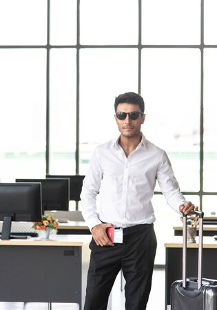 Young and smart businessman with sunglasses, suitcase and travel document such as air ticket, hotel booking document and passport with travel concept,summer vacation concept, summer holiday conceptの写真素材