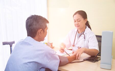 Healthcare and medical concept. Asian professional woman doctor with medical equipment measuring elder patient's blood pressure and pulse.の写真素材