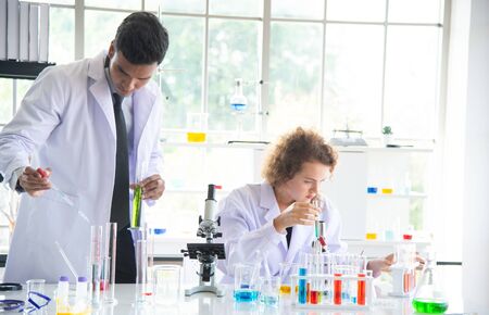 Young woman and man reserchers, scientists, technicians or students conducting research or...