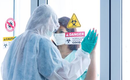 COVID-19, Corona Virus outbreak quarantine and epidemic spread healthy ideas concept. Asian doctors wear PPE personal protection equipment glove and face mask encourage depressed CORONA or COVID-19 patient infectionの写真素材