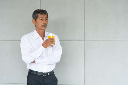 Aging businessman or retirement man have a good health drinking organic and fresh orange juice and thinking seriouslyの写真素材