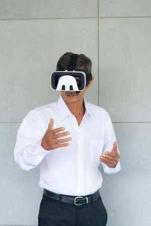 Asian man with white shirt playing game by using virtual reality device in living roomの写真素材