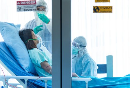 Doctors in protective suit vaccinate and monitor blood pressure the patient infected with VISRUS in...