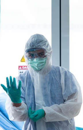 Doctors in protective suit wear medical rubber gloves looking at camera in front of VISRUS or...