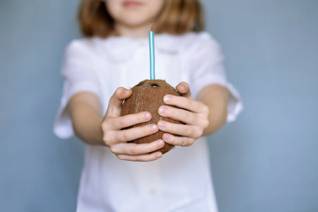 girl playing with coconut. girl eating tasty coconut. children and healthy food. hands holding coconutの写真素材