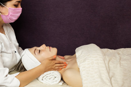 Top view of cosmetologist do facial mask for healthy glowing skin for smiling female client. Dermatologist make beauty procedures for woman patient in aesthetic medical clinic. Cosmetology concept.の写真素材