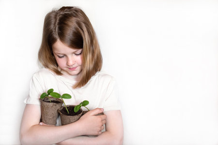 Healthy seedlings, hobby gardening. cute girl examines and plays with plants at home on the windowsill. concept of learning and care. girl with organic plants on white background.の写真素材
