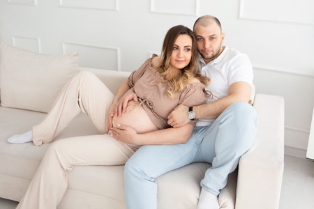 young pregnant woman with her family at home. beautiful family. man hugging pregnant woman.の写真素材