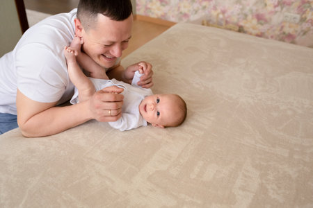 close-up dad plays with a small child at home on the bed. parent hugging a small child. family...