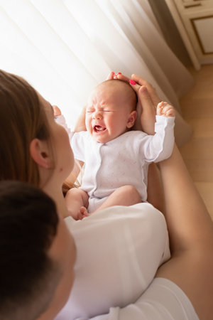 young parents hold the baby in their arms. family lifestyle photo with baby. family concept. baby crying in parent's arms.の写真素材