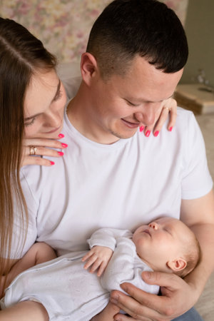 young parents hold the baby in their arms. dad and mom hug a small child. happy family relaxing at...