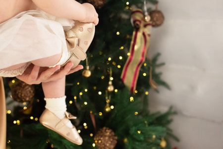 legs of a little girl in golden shoes against the background of a Christmas tree. christmas and new year concept.の写真素材