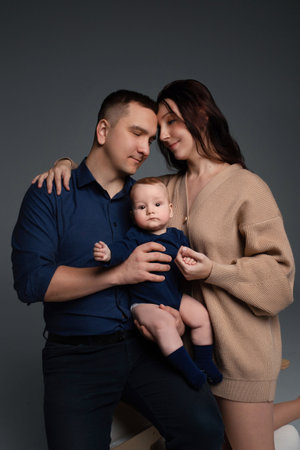 close-up portrait of happy parents hugging their little son in their arms. photograph on a dark...