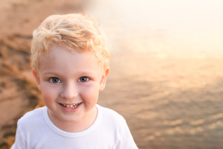 portrait of a little smiling boy with white curly hair on the seashore.の写真素材
