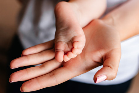 the parent's hand holds the baby's small leg, light close-up photo. family concept.の写真素材