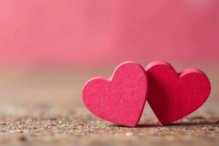 two pink wooden hearts stand on a wooden background for valentine's day.の素材