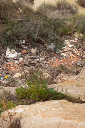 A rocky viewpoint reveals a contrasting scene, where beautiful nature meets an unfortunate accumulation of waste materials and debris, highlighting environmental challenges in the region.の写真素材