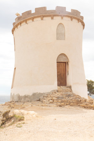 Visitors marvel at the historic tower located on a rocky outcrop overlooking the Mediterranean Sea in Spain.の写真素材
