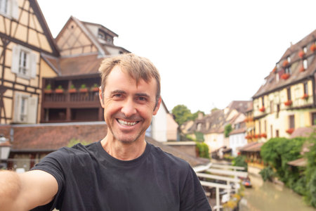 Tourists enjoying their family vacation in Colmar, taking a selfie against the charming backdrop of...