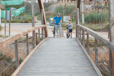 Father and son walking on a wooden bridge over the sea in the villageの写真素材