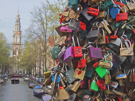 Hundreds of padlocks (called love locks) on a bridge crossing a canal (so called gracht) in Amsterdam, Netherlands. People close these locks on the cables / suspension ropes of the bridge as a sign of eternal love.のeditorial素材