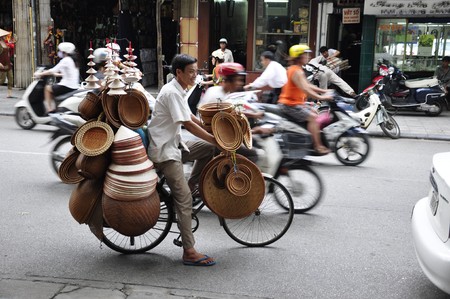 Unidentified hat salesman in the busy hanoi traffic on June 29, 2010 in Hanoi, Vietnamのeditorial素材