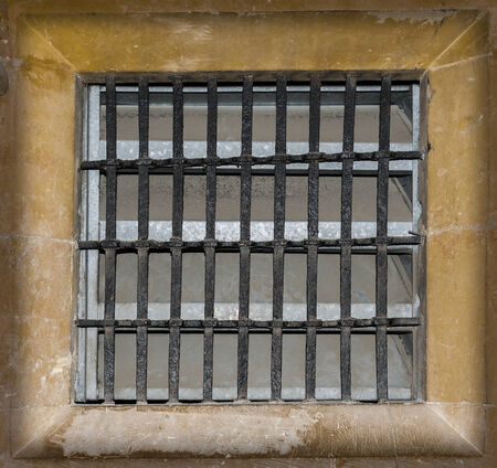 Metal grilled window set in stone workの写真素材
