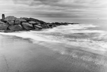 Milky waves splashing over rocks in black and whiteの写真素材