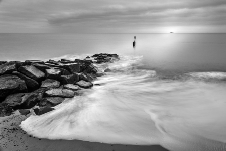 Milky waves splashing over rocks in black and whiteの写真素材