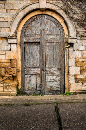 Old decaying wooden double doors in a stone archwayの写真素材