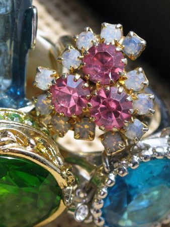 Close-up of pink amethyst and opal ring next to various colored glass rings