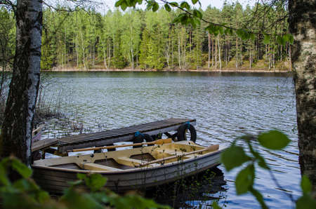 A rowing boat at an old pier in a calm lake in woodland  From the province Smaland in Sweden 