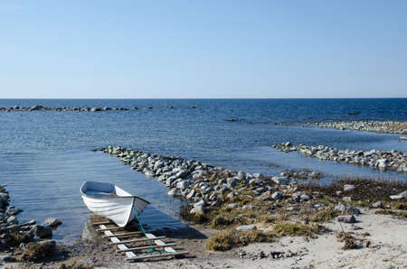 Single moored rowing boat at a rocky coastの写真素材
