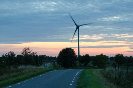 Wind turbine by a winding road at late evening in a rural landscapeの写真素材