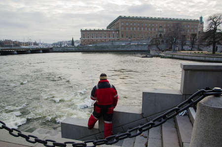 STOCKHOLM, SWEDEN - 28 NOV: The Royal Palace in Stockholm with an angling man by the streaming water. This place, in the center of Stockholm, is very popular  for angling. Photo taken on 28 November 2014 at Str?mmen, Stockholm, Sweden.のeditorial素材
