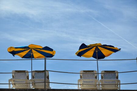 Colorful sun umbrellas and sun beds at blue skyの写真素材
