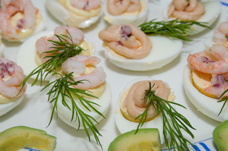 Egg halves decorated with prawns, caviar, dill, red onion and mayonnaise