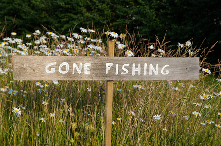 Gone fishing sign on a pole among summer flowersの写真素材