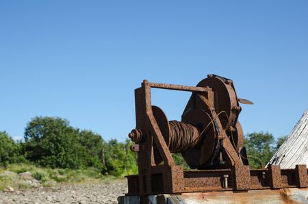 Old rusty and weathered boat winch outdoors at blue skyの写真素材