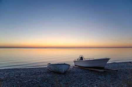 Two boats at a colorful bay at sunset by the coast of Baltic Sea in Swedenの写真素材