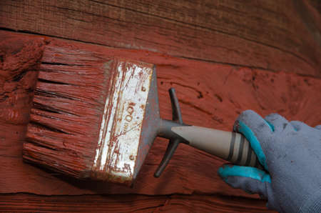 Painting a red and rough exterior wall with a paintbrushの写真素材